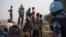 FILE - A United Nations peacekeeper stands with displaced children on a wall around the United Nations base in the capital Juba, South Sudan. 