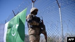 FILE - A Pakistani soldier stands guard next to a fence along Pakistan's border with Afghanistan's Paktika province, in Angoor Adda, in Pakistan's South Waziristan tribal agency, Oct. 18, 2017.