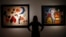 An employee at Christie's poses with Joan Miro's "L'Oiseau au plumage deploye vole vers l'arbre argente" (R) and "Painting (Women, Moon, Birds)" in London, Jan. 8, 2015.