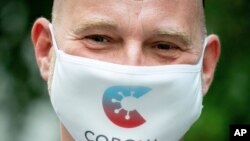 Rainer Knirsch, Telekom press spokesman, wears a mouth and nose protector with the app's logo at the beginning of a press conference on the 100-day Corona Warning App at the Federal Press Conference Center in Berlin, Sept. 23, 2020.