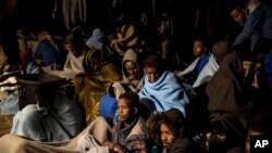 FILE - In this photo taken Feb. 18, 2018 photo, refugees and migrants sit on the deck of a rescue ship after being rescued by aid workers of the Spanish NGO Proactiva Open Arms. 