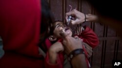 FILE - A Pakistani child receives a polio vaccine by a health worker in Islamabad, Nov. 26, 2013. 