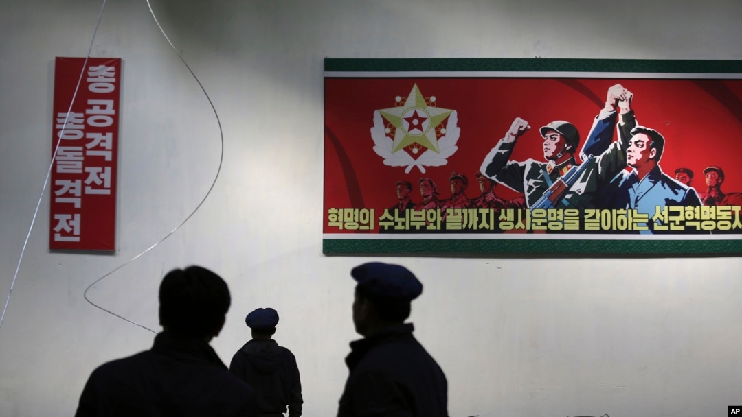 북한 평양326전선공장에 게시된 구호 앞으로 근무자들이 지나가고 있다. (자료사진)