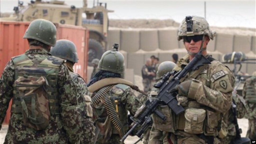 Afg'on zobitlari (chapda) AQSh askarining yonidan o'tib ketmoqda. Kobul, Afg'oniston, 11-mart, 2012-yil.