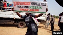 Une femme tient un panneau "Je crois au président Muhammadu Buhari pour redonner au Nigeria sa grandeur" à Abuja, Nigeria, le 6 février 2017. 