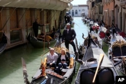 Para wisatawan menikmati perjalanan naik gondola di Venesia, Italia, Kamis, 25 April 2024. (Luca Bruno/AP)