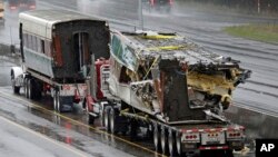 Two damaged train cars sit on flatbed trailers after being taken from the scene of an Amtrak train crash in DuPont, Washington, Dec. 19, 2017.