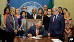 Washington Gov. Jay Inslee signs House Bill 1465 into law, May 7, 2019, at the Capitol in Olympia, Wash. The bill strengthens requirements for pistol sales or transfers in the state, and was one of several gun-related bills signed into law Tuesday.