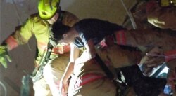 In this photo taken from video provided by ReliableNewsMedia, firefighters rescue a survivor from the rubble of the Champlain Towers South Condo after the multistory building partially collapsed in Surfside, Fla., June 24, 2021.