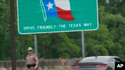 Seorang petugas Patroli Keamanan Publik Texas berjalan setelah berbicara dengan pengemudi di tempat pemberhentian, di Orange, Texas, 30 Maret 2020. (Foto: AP)