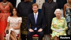 Britain's Queen Elizabeth, Prince Harry and Meghan, the Duchess of Sussex pose for a picture with some of Queen's Young Leaders at a Buckingham Palace reception following the final Queen's Young Leaders Awards Ceremony, in London, Britain June 26, 2018. 