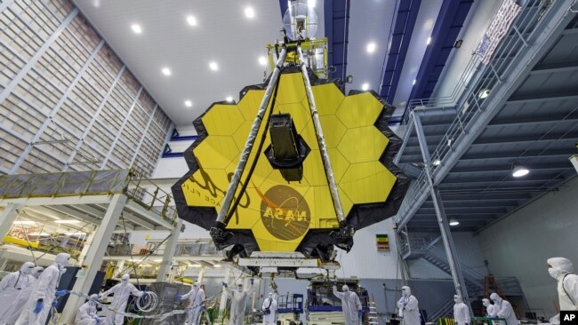 En esta fotografía de 2017 difundida por la NASA, varios técnicos elevan el espejo ensamblado del Telescopio Espacial James Webb.