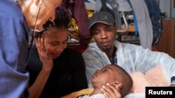 A migrant child lies in his mother's arms in the hospital ward of the Alan Kurdi vessel, run by the German charity Sea-Eye, in the Mediterranean sea, April 3, 2019. 