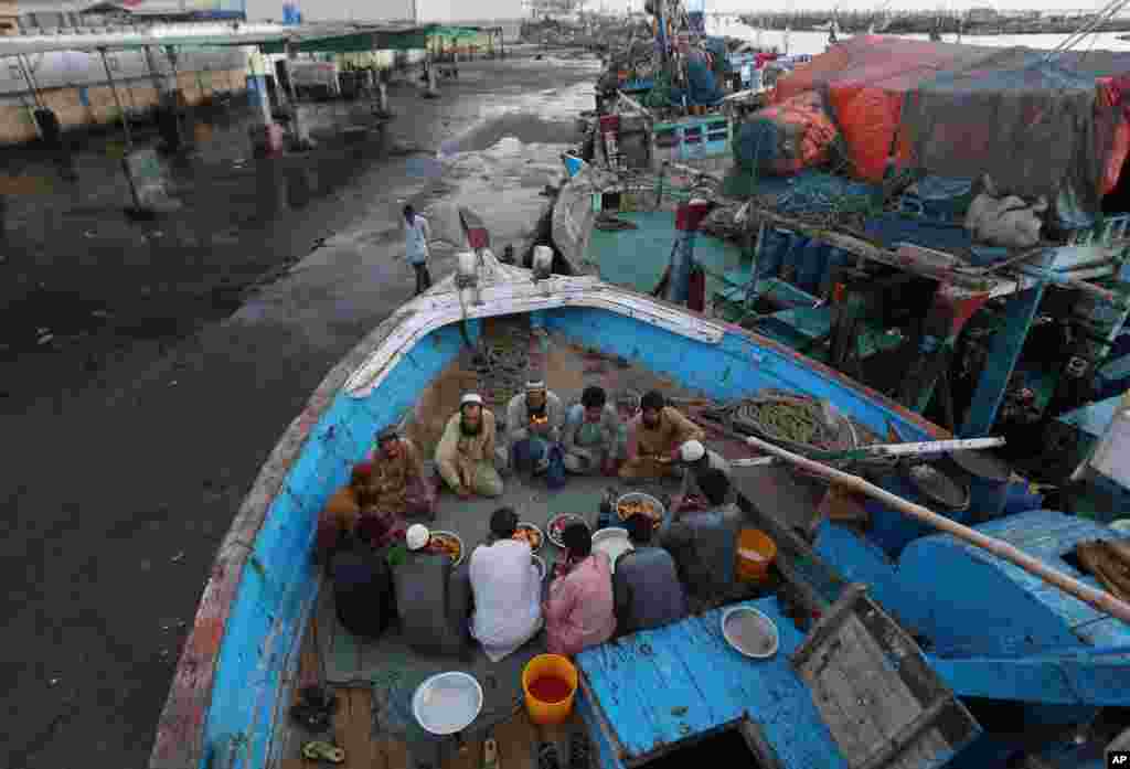 افطار گروهی از ماهی‌گیران مسلمان در اسکله‌ای در کراچی، پاکستان