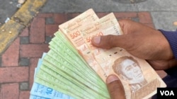 Un ciudadano sostiene un fajo de bolívares, la moneda local venezolana, en Caracas, Venezuela. [Foto de archivo]
