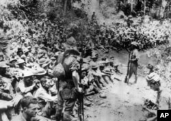 FILE - In this 1942 file photo provided by U.S. Marine Corps, Japanese soldiers stand guard over American war prisoners just before the start of the Bataan Death March following the Japanese occupation of the Philippines.