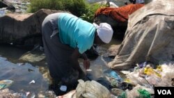 FILE: A woman is seen washing clothes in the Mukuvisi River in Harare, Zimbabwe, Sept. 11, 2018, as water shortages persist, what experts say is fueling the spread of cholera. (C. Mavhunga/VOA)