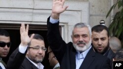 Perdana Menteri Gaza Ismail Haniyeh (kanan) dan Perdana Menteri Mesir Heshan Kandil (kiri) melambaikan tangan ke para hadirin saat bertemu di Kota Gaza (16/11). Israel menawarkan diri untuk menghentikan serangan di Gaza selama kunjungan PM Mesir ke negaranya hari ini.