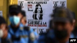 Miembros de la Policía Nacional hondureña se paran frente a un letrero que dice "Keyla Martínez no se suicidó, investigue y castigue a la policía", en La Esperanza, Honduras, el 9 de febrero de 2021.