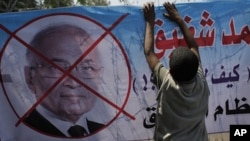 An Egyptian youth hangs a banner with a defaced picture of presidential candidate, Ahmed Shafiq and Arabic that reads "Shafiq, the former regime," during a protest in front the Supreme Constitutional Court in Cairo, Egypt, June 14, 2012.