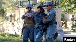 Afghan policemen help an injured comrade at the site of a suicide bomb attack in Ghazni Province, September 4, 2014.