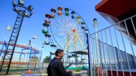 A security guard sits at an empty amusement park, on the first day of the Muslim holiday of Eid al-Fitr, amid concerns over the spread of the coronavirus disease (COVID-19), in the port city of Sidon, southern Lebanon, May 24, 2020. (AP photo)