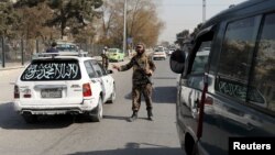 A Taliban fighter stands as he guards a checkpoint in Kabul, Afghanistan Nov. 27, 2021. 