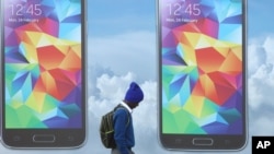 A schoolboy walks beneath a mobile phone advertising billboard in Johannesburg on Sept. 3, 2014. (AP Photo/Denis Farrell)