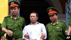 FILE - Police officers escort French-Vietnamese math professor Pham Minh Hoang out of a courthouse in Ho Chi Minh City, Aug. 10, 2011.