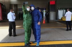 A couple decked out in full protection suits against the spread of the new coronavirus take a selfie while waiting for the arrival of their son in one of the firsts international flights from United States, in Quito, Ecuador, June 4, 2020.