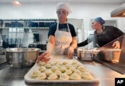 FILE- Ukrainian refugee women working at a Ukrainian food bar that a private foundation has opened to offer jobs to the refugees, in Warsaw, Poland, on Friday, April 1, 2022. (AP Photo/Czarek Sokolowski)