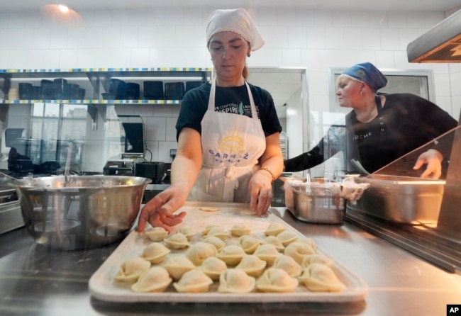 FILE- Ukrainian refugee women working at a Ukrainian food bar that a private foundation has opened to offer jobs to the refugees, in Warsaw, Poland, on Friday, April 1, 2022. (AP Photo/Czarek Sokolowski)