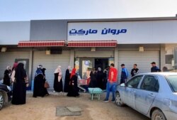 FILE - Libyans queue outside a supermarket in Tripoli on April 19, 2020.
