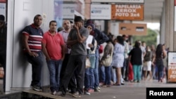 People line up before filling out applications while looking for job opportunities, in front of the building of an employment agency in Brasilia, Brazil, March 8, 2016.