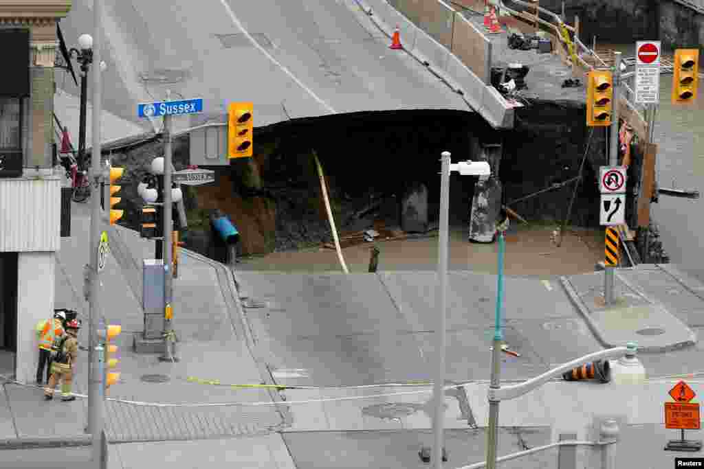 Workers look at a large sinkhole in Ottawa, Ontario, Canada, June 8, 2016.
