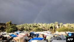 FILE —- A rainbow appears across the sky as internally displaced Palestinians who fled the Israeli military bombardment and incursion into the northern Gaza Strip, shelter in makeshift tents in Khan Yunis in the southern Gaza Strip on November 15, 2023.