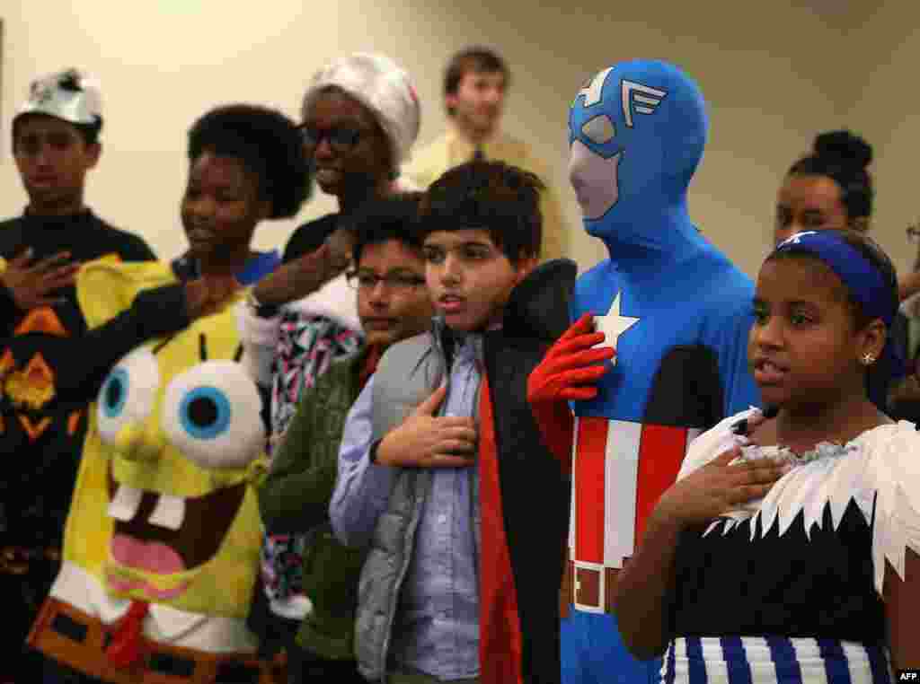 Children wearing Halloween costumes recite the Pledge of Allegiance after becoming US citizens during a naturalization ceremony at the United States Citizenship and Immigration Services in Baltimore, Maryland. 