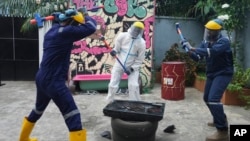 People wearing protective gear use sledgehammers to break a television set to vent their anger outside the Shadow Rage Room in Lagos, Nigeria, July 28, 2024.