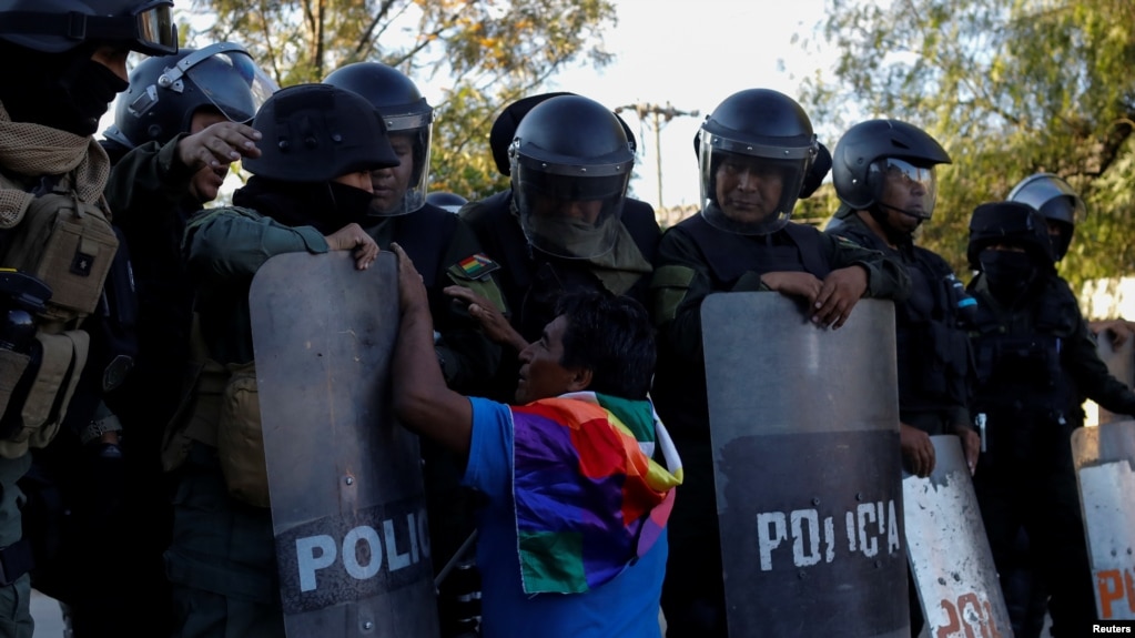 Un partidario del expresidente de Bolivia, Evo Morales, se arrodilla y hace gestos frente a miembros de las fuerzas de seguridad, durante una manifestación en Cochabamba, Bolivia, el lunes.