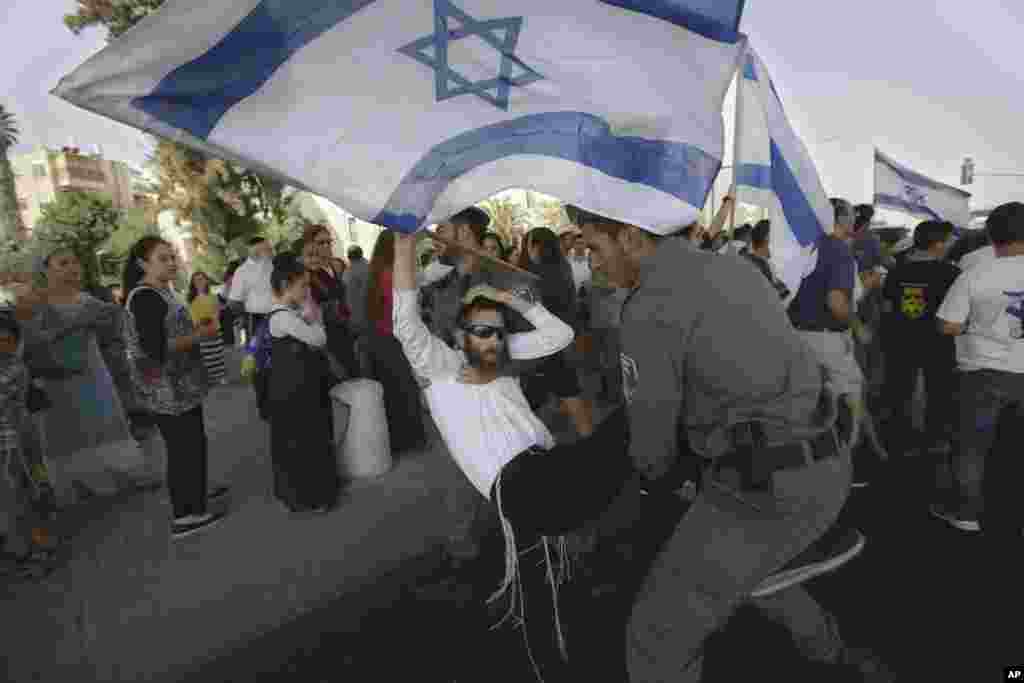 Polisi perbatasan Israel membawa seorang demonstran sayap kanan setelah ia mencoba menghalangi jalam dalam sebuah demonstrasi, sehari setlah penembakan oleh penembak Palestina yang menewaskan sepasang suami istri Yahudi yang sedang berkendara dengan anak-anak mereka, di Yerusalem (2/10). (AP/Sebastian Scheiner)