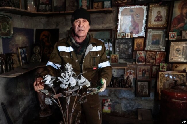 Viktor Mikhalev shows roses transformed from weapons and ammunition into flowers of war standing in a workshop in his house in Donetsk. (AP Photo/Alexei Alexandrov)