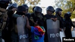 Un partidario del expresidente de Bolivia, Evo Morales, se arrodilla y hace gestos frente a miembros de las fuerzas de seguridad, durante una manifestación en Cochabamba, Bolivia, el lunes.