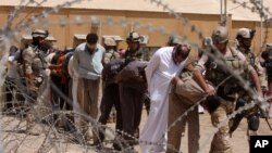 FILE - Blindfolded and handcuffed suspected al-Qaida members are led away to detention centers in an Iraqi army base in Hillah, Iraq, July 20, 2012.