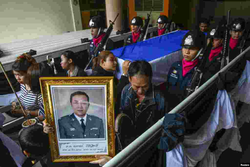 Relatives and mourners lead a procession to a temple for the funeral ceremony of Narong Pitisitthi, 45, a policeman who died after being shot during the clashes between anti-government protesters and riot police, Bangkok, Thailand, Dec. 27, 2013.