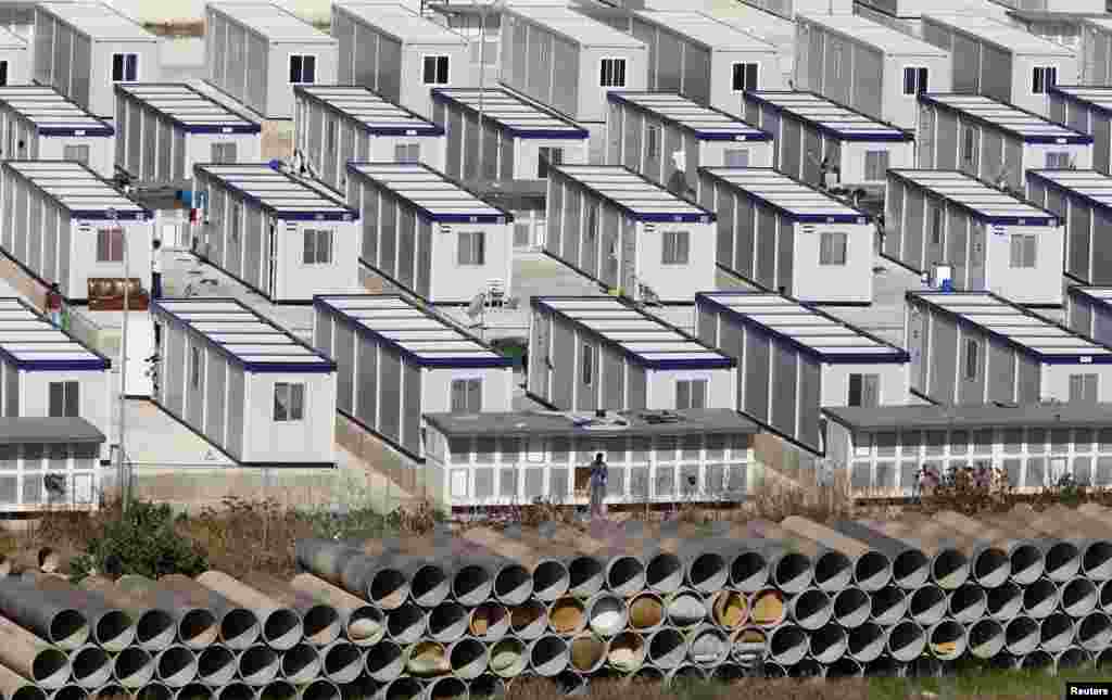 African immigrants walk among rows of prefabricated container houses, which have replaced scores of tents, at the open center for immigrants formerly known as &quot;Tent City&quot; in Hal Far, outside Valletta, Malta. Some 450 immigrants who have been granted humanitarian protection live in the center, according to UNHCR