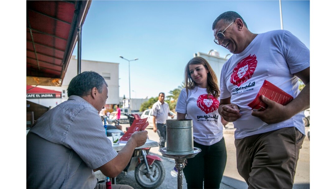 Parliamentary election candidate Yeah Loumi, right, of the Kalb Tounes (The heart of Tunisia) party, talks with man in a cafe outside Tunis, Oct.1, 2019.