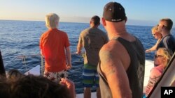 FILE - This Jan. 21, 2016, file photo shows tourists looking out on the horizon as their boat searches for dolphins in waters off Waianae, Hawaii.