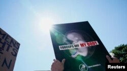 Un manifestante a favor del fallo muestra un cartel que expresa "fórceps, lejos de mi cuerpo", frente a la Corte Suprema, en Washington DC, el 25 de junio de 2022.
