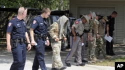 Law enforcement officials conduct a grid search of an area where police say a gunman was being served an eviction notice when he opened fire from inside a home near Texas A&M and killed a law enforcement officer Monday, Aug. 13, 2012, in College Station,