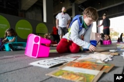 A students from Public School 11 picks out art supplies during an art class at the High Line Park Wednesday, Oct. 21, 2020, in New York. (AP Photo/Frank Franklin II)